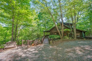 A rustic cabin with a porch, surrounded by dense trees. - Swan Way Mountain Retreat (Lake Lure)