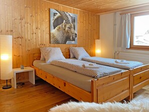 Una habitación con paneles de madera, una cama, una mesita de noche, una lámpara y un ventanal con cortinas.