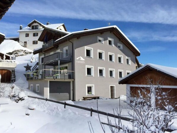 Ein mehrstöckiges Hotel mit einer Seilbahn im Hintergrund, was auf eine Lage in der Nähe eines Skigebiets hindeutet.