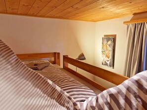 A bunk bed with striped bedding, a wooden headboard, and a painting of a cat on the wall. - Casa Radieni, Flond, (Flond), 37000B by Interhome (Obersaxen Flond)