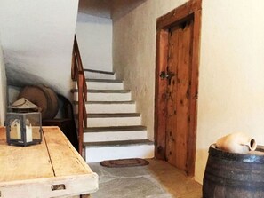 A staircase leading to a wooden door, a barrel, and a table with a lantern. - Casa Radieni, Flond, (Flond), 37000B by Interhome (Obersaxen Flond)