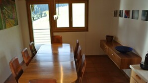Ein Essbereich mit Holztisch und Stühlen, ein Fenster mit Blick und eine Küchenarbeitsplatte mit einer Schüssel.