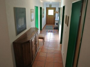 Um corredor com um armário de madeira, um banco e uma porta no final.