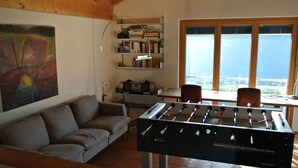 Ein Zimmer mit Tischfußball, einer Couch, einem Bücherregal und einem Fenster mit Blick.