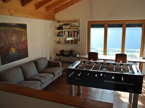 Ein Zimmer mit Tischfußball, einer Couch, einem Bücherregal und einem Fenster mit Blick.