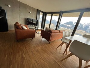 A modern living room with a large window, a flat-screen TV, and a dining area. - Schwalbennest Votteler, Morissen, (Morissen), 43009B by Interhome (Morissen)