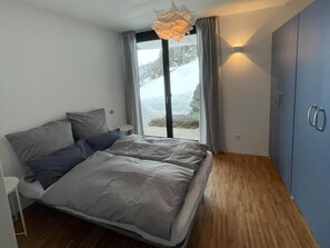 A modern bedroom with a bed, a wardrobe, and a view of the outdoors. - Schwalbennest Votteler, Morissen, (Morissen), 43009B by Interhome (Morissen)