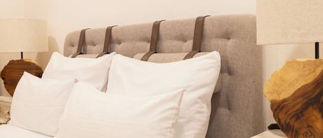 Een bed met witte beddengoed en een hoofdbord met bruine banden.