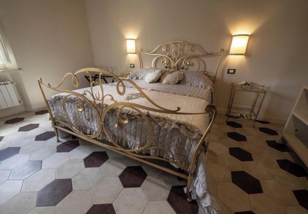 A bedroom with a bed, two wall-mounted lamps, and a radiator.