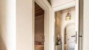 A hallway with a geometric patterned floor, a bed with a headboard, and a hanging light fixture.