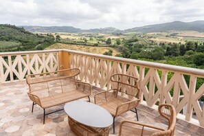 A balcony with wicker furniture and a view of a valley. - Punti Di Vista B&B Food&Wine Experience (Bibbona)