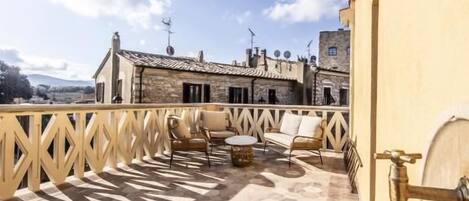 Une terrasse sur le toit, dotée d’un sol en pierre à motifs hexagonaux, de mobilier d’extérieur et offrant une vue sur les bâtiments environnants.