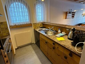 Eine kleine Küche mit Spüle, Wasserkocher und Kaffeemaschine.