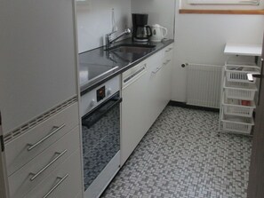 Una cocina compacta con fregadero, cafetera y horno pequeño.