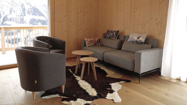 Een gezellige kamer met een bank, fauteuil en een klein rond tafeltje.