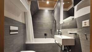 Een moderne badkamer met een badkuip, toilet en wastafel.