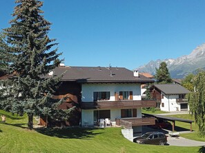 A two-story house with a balcony, a driveway, and a parked car.