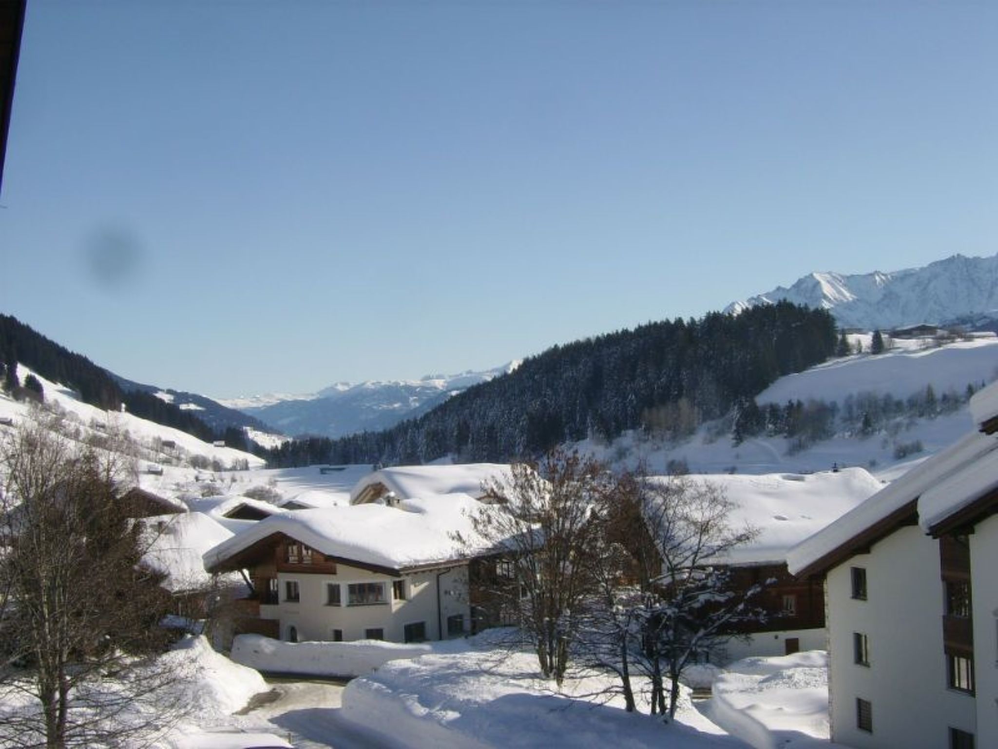 Een bergdorp bedekt met sneeuw, met traditionele houten huizen en een heldere lucht.