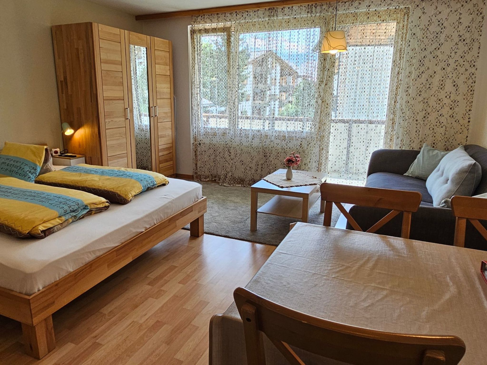 Ein Zimmer mit einem Bett, einem Schlafsofa, einem Tisch und einem Kleiderschrank.