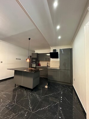A modern kitchen with a marble countertop, stainless steel appliances, and pendant lighting. - Villa Badia (Empuriabrava)