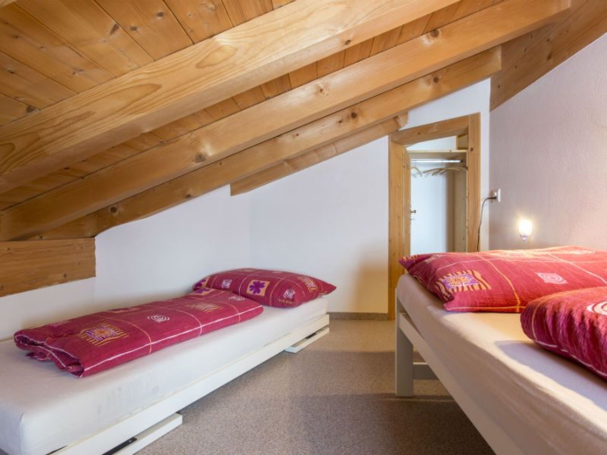 A small, single-room accommodation with two beds, a wooden ceiling, and a simple, uncluttered layout.