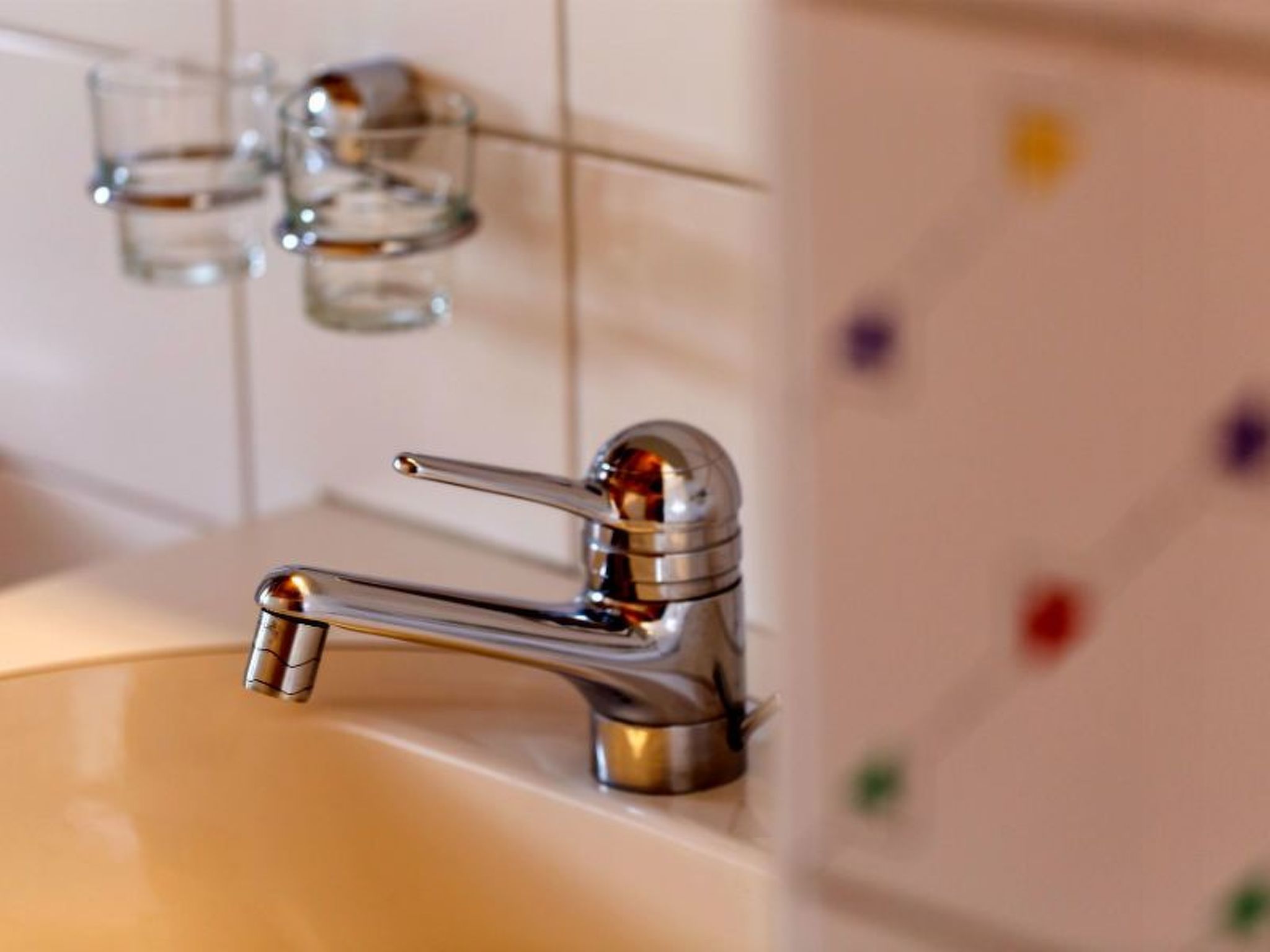 A bathroom with a chrome faucet and a mirror.