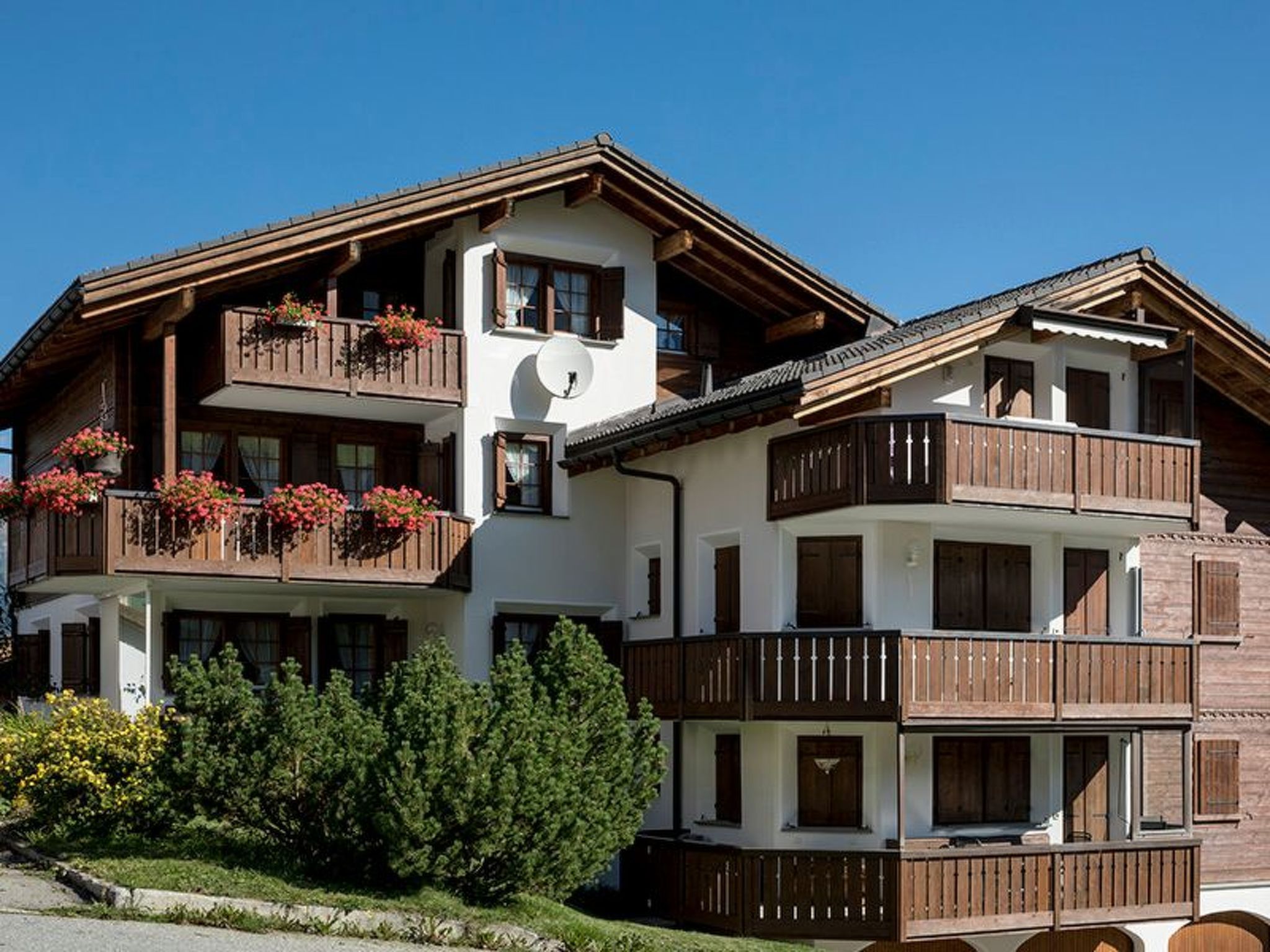Un immeuble à plusieurs étages doté de balcons, de rampes en bois et de jardinières.