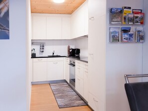 Una cocina compacta con armarios blancos, una cafetera negra y un tapete pequeño.