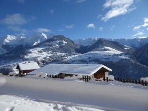 Un paysage de montagne enneigé avec une cabane en bois et une clôture en bois.