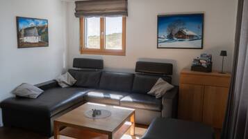 Ein modernes Wohnzimmer mit einem Ecksofa, einem Couchtisch und zwei Bildern an den Wänden.
