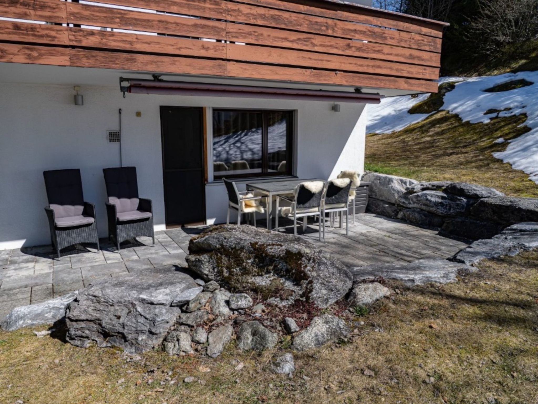 Ein modernes Gebäude mit einer Terrasse, Sitzgelegenheiten im Freien und Blick auf eine verschneite Landschaft.