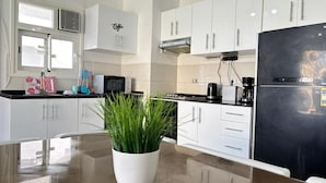 A modern kitchen with white cabinets, a black refrigerator, and a potted plant on the counter. - Fouka North Coast CL3-TW3X-A-G (Marsa Matrouh)