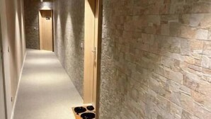 A hallway with stone walls, wooden doors, and a carpeted floor. - Elegance & Terrace in the heart of the 5 Cantons - Beaches on foot (Anglet)