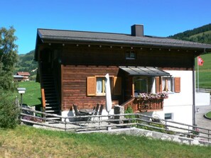 Eine Holzhütte mit einem Balkon, einem kleinen Tisch und Stühlen sowie einem Blumenkasten.