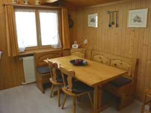 Ein Essbereich mit Holztisch, Stühlen, einem Heizkörper und einem fenster mit Vorhängen.