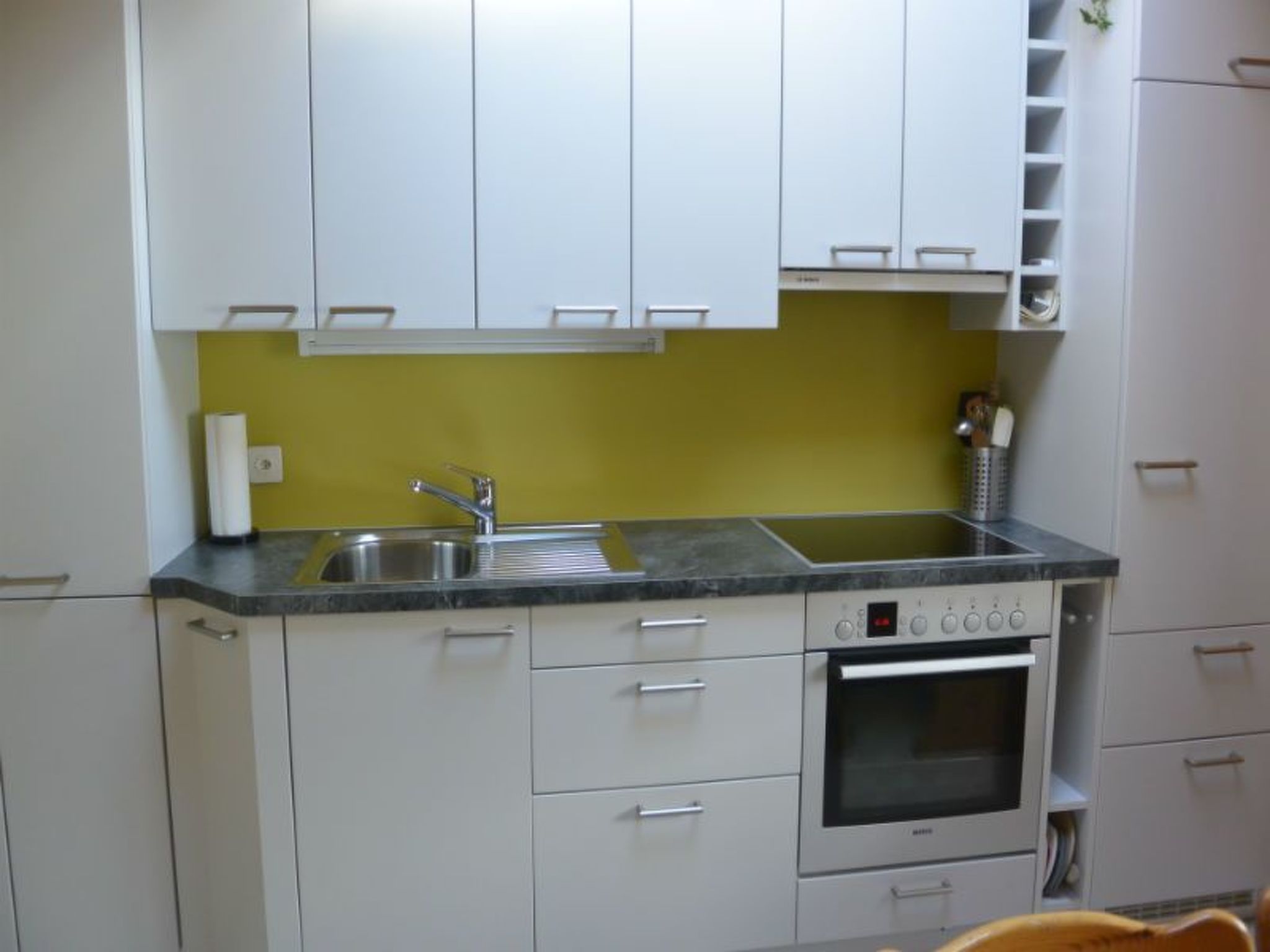 Una cucina compatta con lavello, forno e pensili.