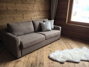 Een kamer met houten lambrisering, een bank en een bont tapijt.