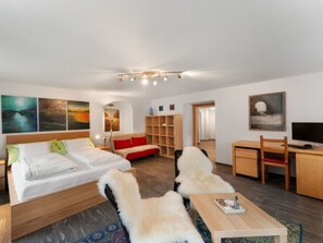 Una habitación de hotel moderna con cama, sofá, escritorio con computadora y televisor.