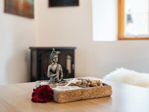 A statue of a seated figure on a table with a flower and a stone container. - Pacifica und Romantica in Cumpadials, (Cumpadials), 76002B by Interhome (Cumpadials)