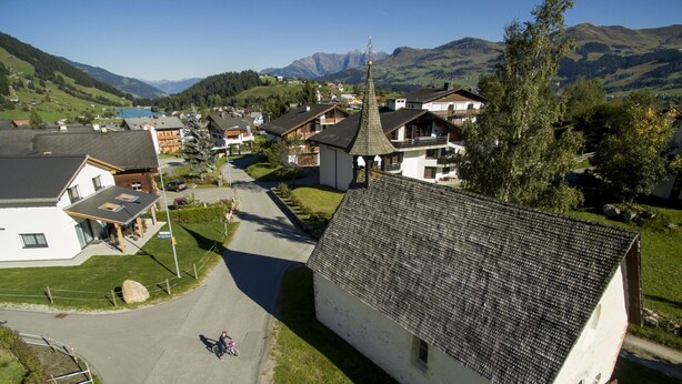 A rural village with traditional houses, a church, and a mountain backdrop. - Flurina 19 Defuns, Brigels, (Breil/Brigels), 65023B by Interhome (Breil/Brigels)