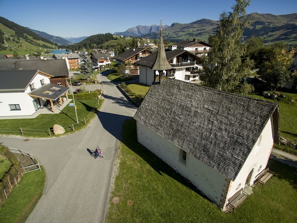 Un village rural avec des maisons traditionnelles, une église et une chaîne de montagnes en arrière-plan.