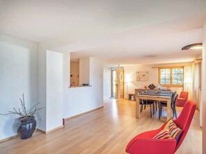 A spacious living area with a dining table and chairs, a red armchair, and a potted plant. - Alprüüsch, Obersaxen-Misanenga, (Obersaxen), 34155B by Interhome (Obersaxen Affeier)