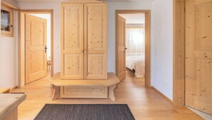 A room with wooden doors, a bench, and a bed with white bedding. - Alprüüsch, Obersaxen-Misanenga, (Obersaxen), 34155B by Interhome (Obersaxen Affeier)