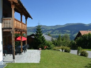 A wooden building with a balcony, a stone patio, and a view of mountains. - Ferienhaus Casa Patricia, Brigels, (Breil/Brigels), 65046B by Interhome (Breil/Brigels)