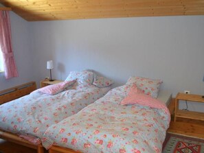 A bedroom with two single beds, a nightstand with a lamp, and a checkered curtain. - Ferienhaus Casa Patricia, Brigels, (Breil/Brigels), 65046B by Interhome (Breil/Brigels)