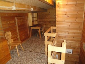 A wooden interior with a carpeted floor, a wooden table, a chair, and a bench. - Gadola, Obersaxen-Meierhof, (Obersaxen), 34069B by Interhome (Obersaxen Affeier)