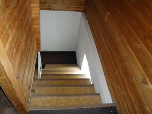 A wooden staircase with a dark landing area and a white wall at the top. - Gadola, Obersaxen-Meierhof, (Obersaxen), 34069B by Interhome (Obersaxen Affeier)