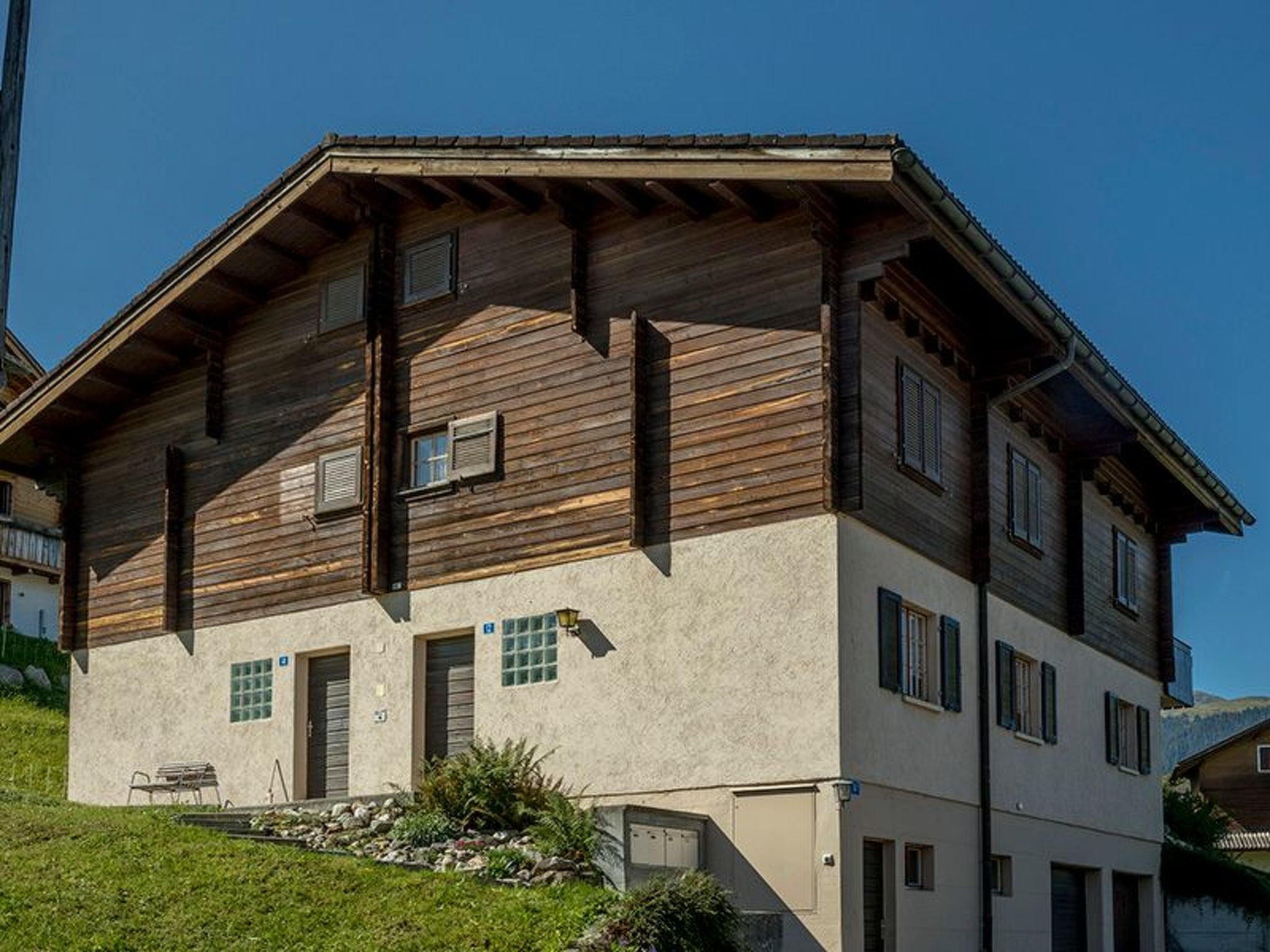 A multi-story building with a sloped roof, wooden exterior, and multiple windows.