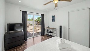 Un dormitorio con cama, escritorio, televisor y ventilador de techo.