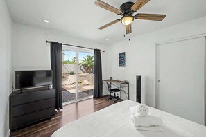 Ein Schlafzimmer mit einem Bett, einem Schreibtisch, einem Fernseher und einem Deckenventilator.